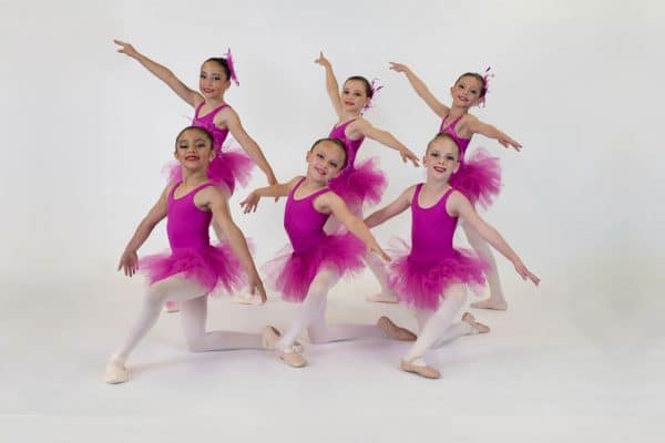Six young girls dancing in ballet uniform.