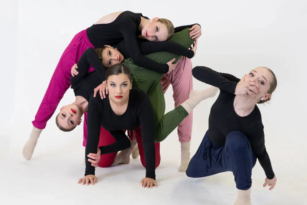 A group of girls tangled up in an elaborate dance move.